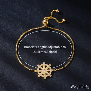 Detail view of a gold-plated adjustable bracelet with zircon micro-paved ship wheel charm