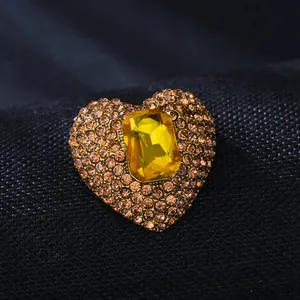 Macro view of a luxurious heart-shaped brooch with amber rhinestones and a yellow gem.