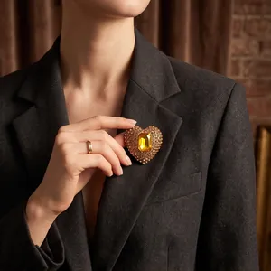 Elegant heart-shaped amber crystal brooch pinned on a professional grey blazer lapel