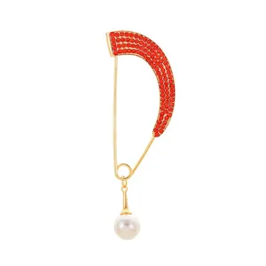 Fashionable gold safety pin brooch with red rhinestones and a white pearl charm
