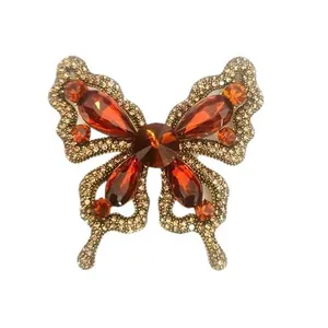 Vintage European butterfly brooch with orange gemstones and crystal-embellished wings.
