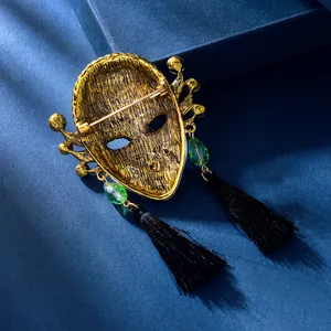 Detailopname van vintage koningin masker broche met groene kristallen en kwastjes