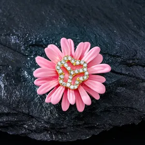 Primer plano de un elegante broche de margarita rosa con un centro brillante de diamantes