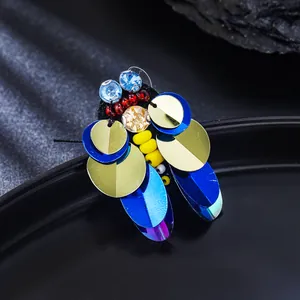 Gros plan d'une broche abeille artisanale en paillettes et strass bleus.
