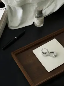 Makroansicht von minimalistischen polierten S925 Silber Wassertropfen-Creolen auf einer Karte