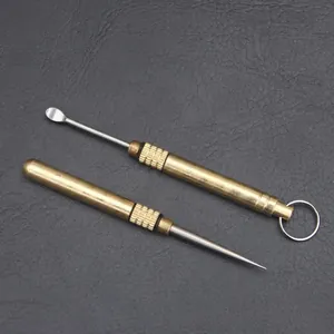 Portable brass and titanium alloy toothpick and ear scoop set on dark background.