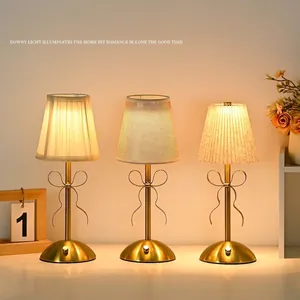 Elegant gold bow table lamps with pleated fabric shades and USB charging for cozy bedroom.
