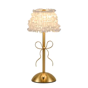 Elegant gold table lamp with white ruffled shade and bow detail for bedside decor