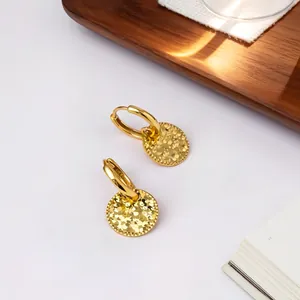 Primer plano de elegantes pendientes de aro en plata 925 con discos dorados texturizados.