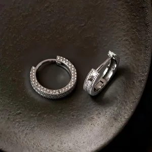 Macro de pendientes de aro de plata de ley S925 con textura de escamas brillantes.