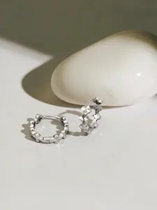 Dettaglio di orecchini a cerchio a quadrifoglio in argento sterling S925 testurizzati
