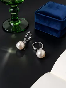 Vista detallada de pendientes de aro de plata S925 con perlas brillantes y textura grabada