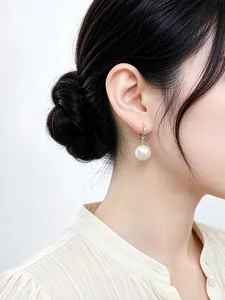 Primer plano de elegantes pendientes de aro en plata 925 con perla en modelo