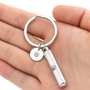 Detailed view of stainless steel cylindrical pet memorial urn keychain in hand