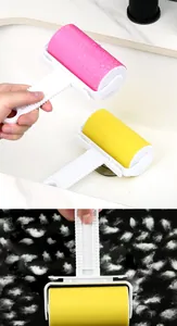 Detail showing washable lint roller effectively removing white fuzz from black fabric surface.