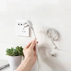 Transparente selbstklebende Wandhaken halten einen Netzstecker und ein weißes Ladekabel