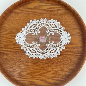 Close-up detail of white hollow lace embroidery patch with delicate pink flower