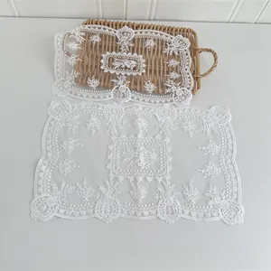 Detailansicht von zwei weiß bestickten Spitzen-Tischsets mit Vintage-Blumenmustern