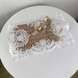 Elegante tovaglietta in pizzo bianco con ricamo floreale su tavolo con servizio da tè