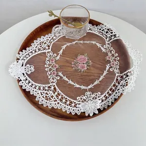 Detail view of embroidered lace mesh applique with floral pattern on a wooden tray