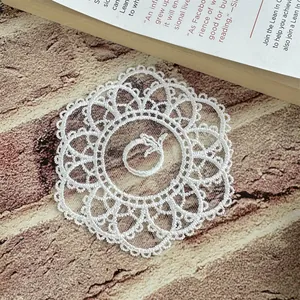 Detailed view of a white circular mesh embroidered lace coaster with floral patterns