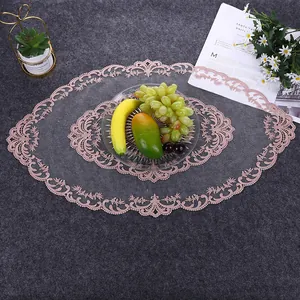 Detail view of a pink oval lace embroidered placemat on a textured grey background