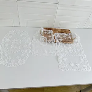 Detailansicht von drei weißen bestickten Spitzen-Tischsets in verschiedenen Formen