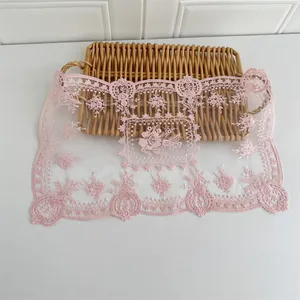 Nahaufnahme eines rosa bestickten Tischsets aus Netzstoff mit Blumenmustern und Wellenrand.