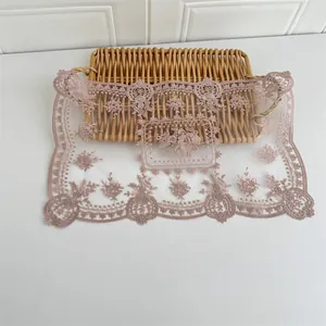 Detailansicht der eleganten Vintage-Blumenstickerei auf staubrosafarbener Spitzentischmatte.