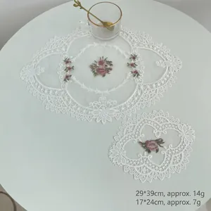 Set of two hollow white lace embroidered table mats with pink floral pattern decoration