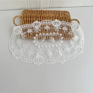 Detailansicht einer weißen bestickten Netz-Unterlage im Vintage-Stil mit feinen floralen Motiven.