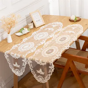Detailed view of white European lace mesh table runner on a wooden dining table