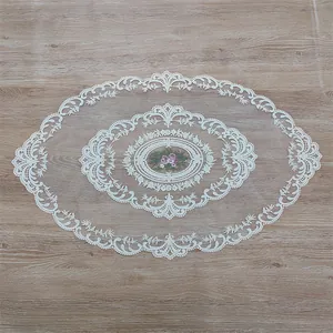 Close-up detail of a white French oval lace doily with elegant floral embroidery