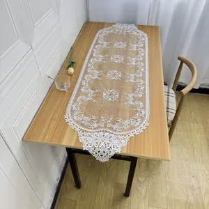 Close-up detail of elegant white lace table runner featuring intricate floral embroidery