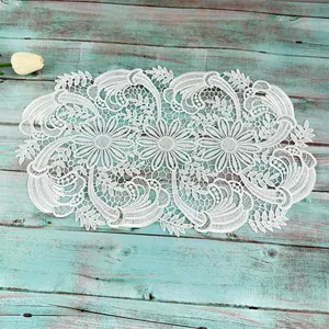 White water-soluble lace doily with elegant floral pattern on turquoise wood
