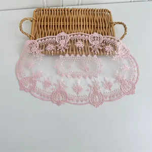 Detailansicht eines rosa Tischsets aus Mesh-Spitze mit exquisitem Blumenstickmuster