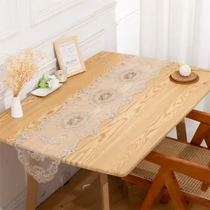 Detailed texture of the vintage lace embroidery on the beige mesh table runner.