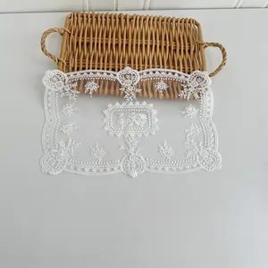 Detailaufnahme eines weißen Spitzendeckchens mit eleganter Blumenstickerei auf Korb