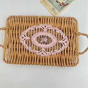 Close-up of pink embroidered lace doily with floral pattern on a wicker tray