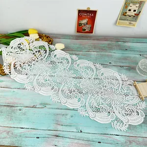 Detailed view of intricate white floral lace table runner on vintage wood background