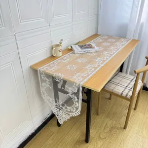 Detailed view of white floral embroidered lace table runner on a wooden table