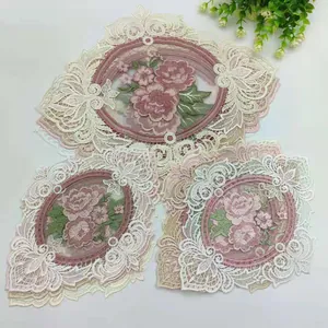 Detail view of pink rose embroidered lace coasters with delicate hollow patterns.