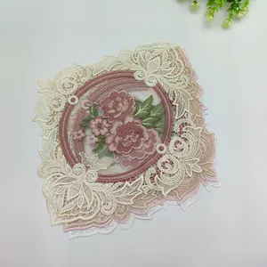 Close-up detail of vintage rose embroidery on a beige lace decorative coaster mat