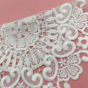 Exquisite detail of white floral embroidered lace coaster on a minimalist pink background