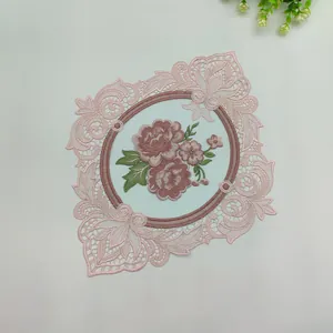 Macro detail of intricate rose embroidery on a pink hollow-out lace decorative mat