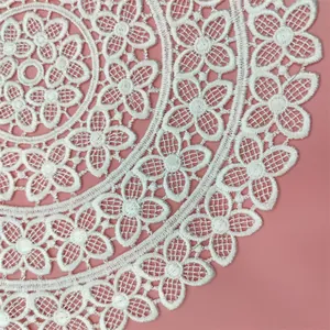 Detailed close-up of a white embroidered circular lace coaster with elegant floral patterns