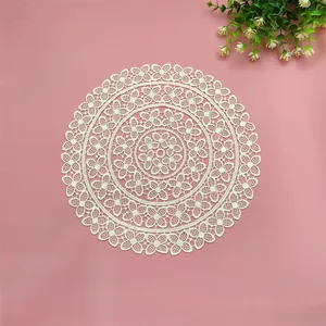 Detailed view of an elegant white circular lace woven coaster on a pink background setting