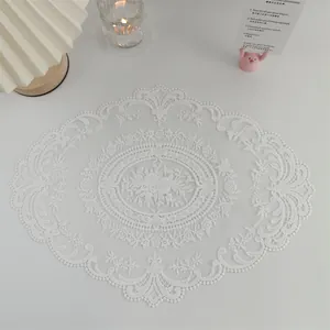 Detailansicht eines eleganten Platzsets aus weißer Spitzenstickerei mit floralen Mustern