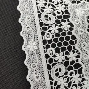 Detailed macro shot of white Korean embroidered lace with intricate floral pattern