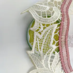Macro detail of intricate white rose embroidery lace with pink scalloped edges